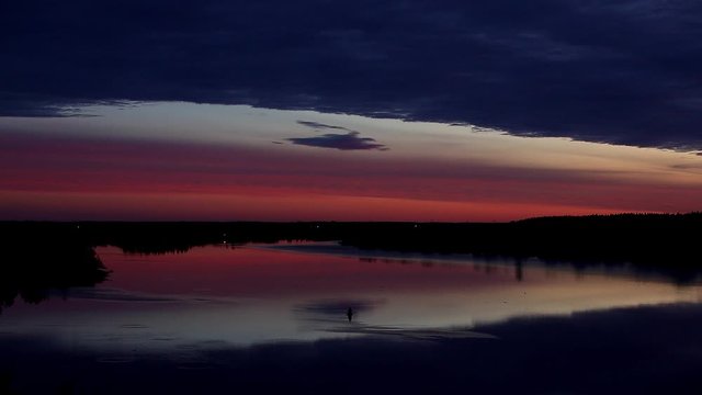 Panorama of the water expanse at dawn with a single buoy on a wide smooth river with a light mist over the water reflecting the pink sky.A night of peace.Russia
