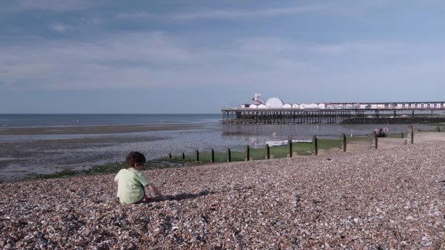 Herne Bay Kent UK. Child throwing stones and playing on the beach in summer