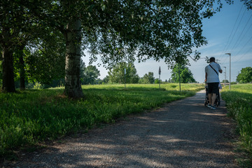 Fototapeta premium Giardino cittadino urbano parco rilassamento con cielo azzurro, passeggiata con carrozzina e telefono