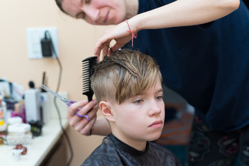 Mom cuts the hair of her son at home during quarantine amid COVID-19 
coronavirus pandemic