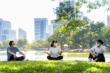 Fototapeta na wymiar Asian young three man and woman talking and relaxing with they friend and wearing mask sitting distance of 6 feet distance protect from COVID-19 viruses for social distancing 