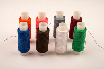 Several reels of multicolored sewing thread on a white background. Close up.