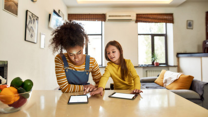 African American woman baby sitter and white little girl reading