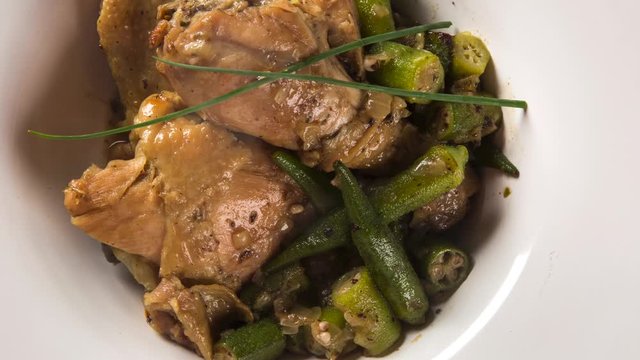 Frango com quiabo (Portuguese for "chicken with okra"), Brazilian dish in white plate with smoke. Top view.