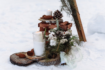 beautiful winter wedding decor with a burning candle and fir branches on a snow background