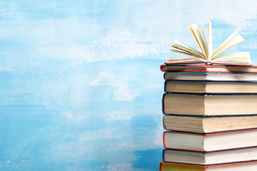 Composition with vintage old hardback books, diary, fanned pages on wooden deck table and red background. Books stacking. Back to school. Copy Space. Education background.