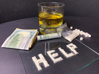 Pills, us dollar banknotes, whiskey and cocaine  on a gray background. Stop drugs concept. A word "help" written with cocaine.