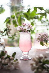 Obraz na płótnie Canvas Refreshing cold cranberry lemonade in a transparent up and apple flowers in a vase are on the table
