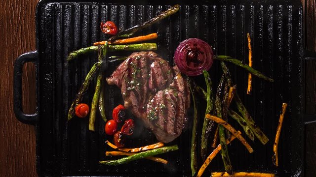 Ancho steak with grilled vegetables on the grill. Top view with smoke.