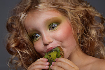 close up portrait of cheerful beautiful little girl. Cute girl eating kiwi