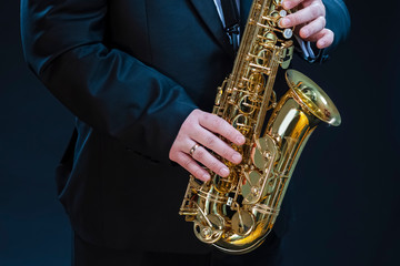 Naklejka premium Closeup of hands of Professional Saxophonist Player Against Black.