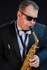 Music Concepts. Portrait of Passionate and Extravagant Caucasian Saxophonist in Dark Suit Posing in...