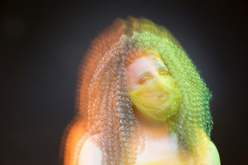 Creative Hair And Makeup Ideas. Sensual Caucasian Girl With Frizzy Colorful Hair and Artistic Facial Mask.Posing Against Black.Mixed Light Used.