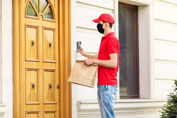 A courier in a protective medical mask delivers takeaway food. Service delivery in terms of quarantine, pandemic coronavirus