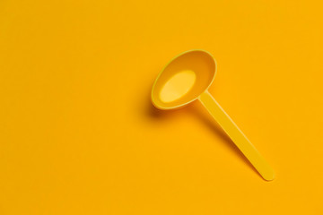 Plastic Yellow Spoon Over Yellow Background.