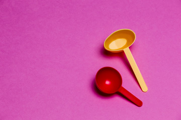 Pair of Colorful Plastic Spoons Placed Together Over Colorful Pink Background