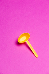 Plastic Yellow Spoon Over Pink Background.