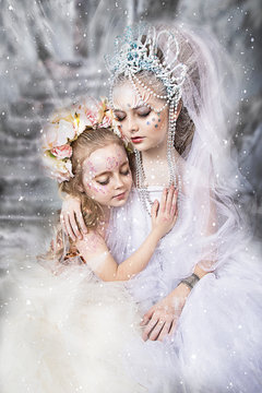 close up portrait of two little sisters. winter and summer. two beautiful sleeping girl in snow. a meeting of winter and summer sisters. professional makeup. beautiful face painting