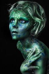 close up portrait of fantastic colorful young girl. professional creative  makeup with beads on face. paint on face. blue and green face art