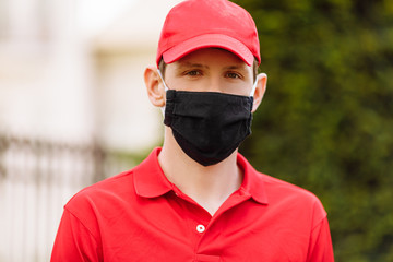 A courier in uniform and wearing a medical protective mask. Fast delivery by transport.Quarantine, coronavirus