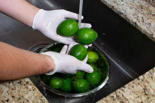 Chef washing lemons with gloves on