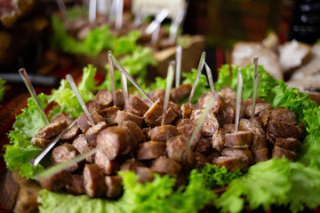 Delicious fried quail with fresh juicy vegetables on the wooden round board on green grass. Roasted Partridge, meat on sunny wedding day.
