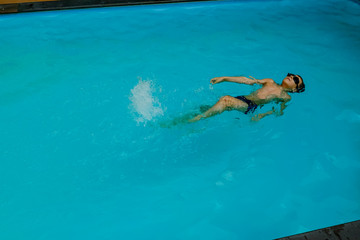 Young boy is swimming on his back in the swimming pool. sport vacation