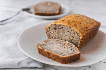 Vegan banana bread loaf cake against white wooden background. Dessert food concept.