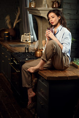 Girl alone in the kitchen. A woman in the dark kitchen at night.