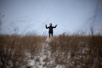 A girl stands in a field in winter.