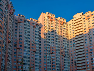 Fototapeta na wymiar Residential facade of a high-rise building with many windows and balconies in the blue sky. Copy space