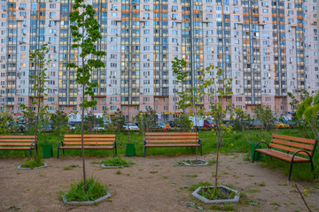 Benches and young trees in the background of a residential building. Copy space. Krasnogorsk, Moscow region, Russia - May 17, 2020