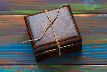 Gift wooden box tied with a rope on a multi-colored wooden background