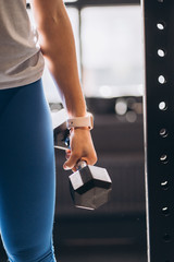 Slender athletic girl performs physical exercises with dumbbells.