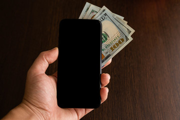 One Red Chilean passport with a black cellphone with a black screen and some bills on a wooden desk