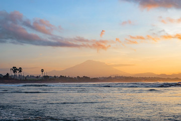 View of the coast, ocean and Agung volcano at sunrise. Beautiful sunrise at Pantai Pabean Ketewel Beach on the east coast of Bali.