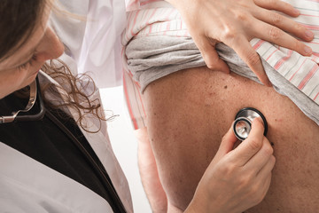 female doctor using a stethoscope on a senior patient