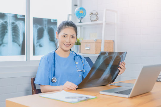 Asian woman  doctors or scientists with stethoscopes indicating something on x-ray picture with laptop, Physician wearing uniform and stethoscope carefully examining diagram. Medicine concept.