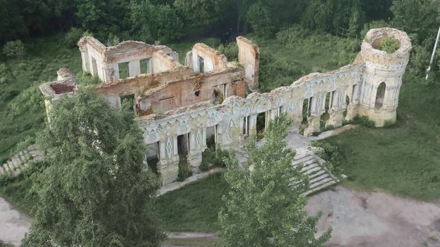 Aerial view of an abandoned ruins of a 19th century manor house among a spring dense forest.