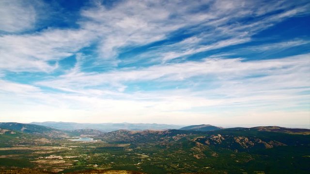 Panorama of white clouds floating over the mountains in blue sky, timelapse