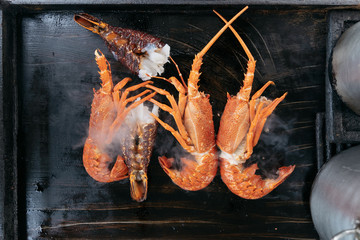 Sizzling hot cooking on the griddle pan. Delicious grilled halved Lobster with butter. Fresh, juicy and tasty Maine Lobster or Crayfish.