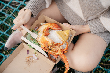Beautiful asian woman holding a lobster claw or crayfish outdoor with beautiful sunlight on sailboat at the beach Kaikoura, New Zealand.
