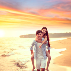 happy young Man Giving Woman Piggyback On Summer Beach