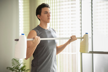 man in confinement doing arm exercise with gallons of water