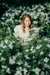 Asian beautiful woman in white dress with white flowers at the park.