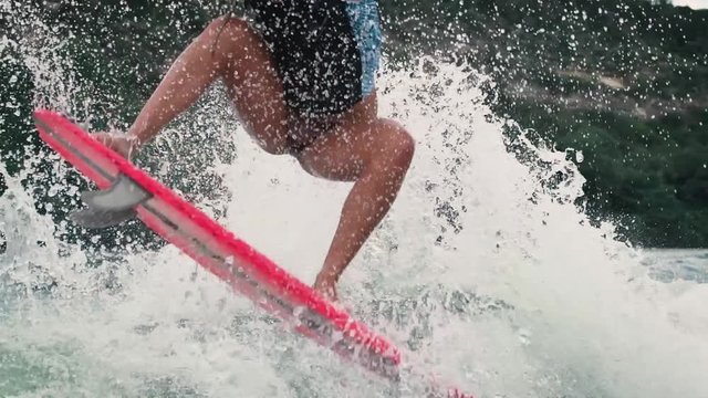 Professional female wake surfer does Ollie in slow motion on big wake behind boat