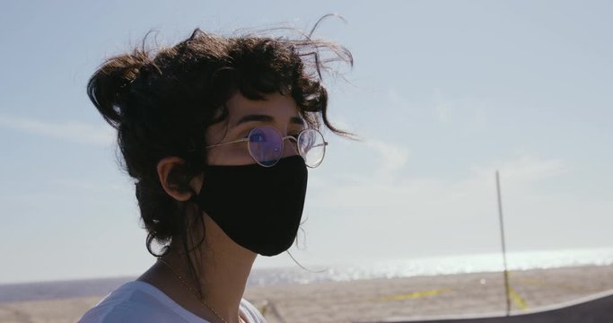 Woman Wearing Face Mask Sitting at Venice Skatepark Los Angeles Staring Listlessly During Corona Virus Pandemic
