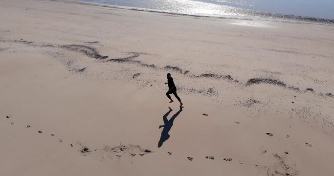 Aerial, drone shot following a man running on a beach, sunny day, on Langeoog island, at the Nordsee, in North Germany