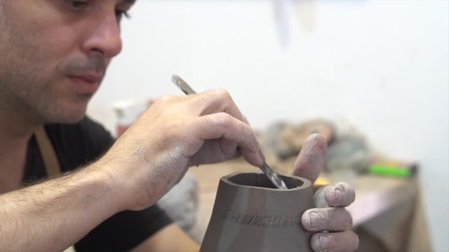 One of the parts of the potter's job is to work on the entire piece, both inside and outside. In this case he is working on an African instrument called ud&uacute;.