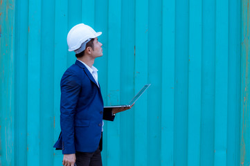 Portrait engineer dock worker under working and checking production process on dock container warehouse by laptop computer,wearing safety uniform.